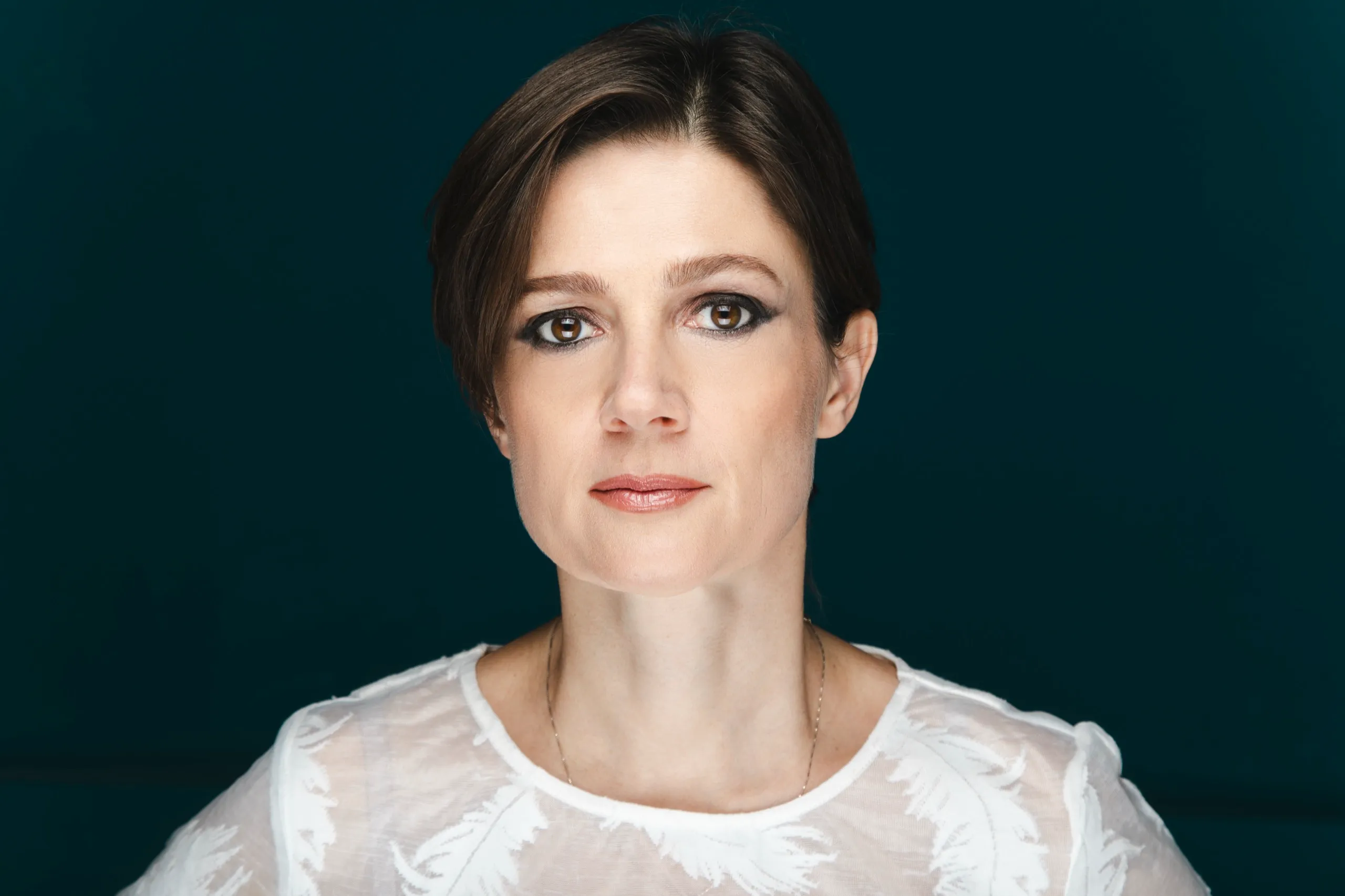 Ritratto di Silvia Bencivelli in camicia bianca su fondo turchese scuro